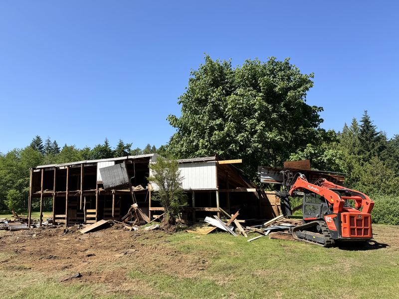 Tearing down an old barn with a compact track loader during a heavy demolition job by Classic Cleanouts