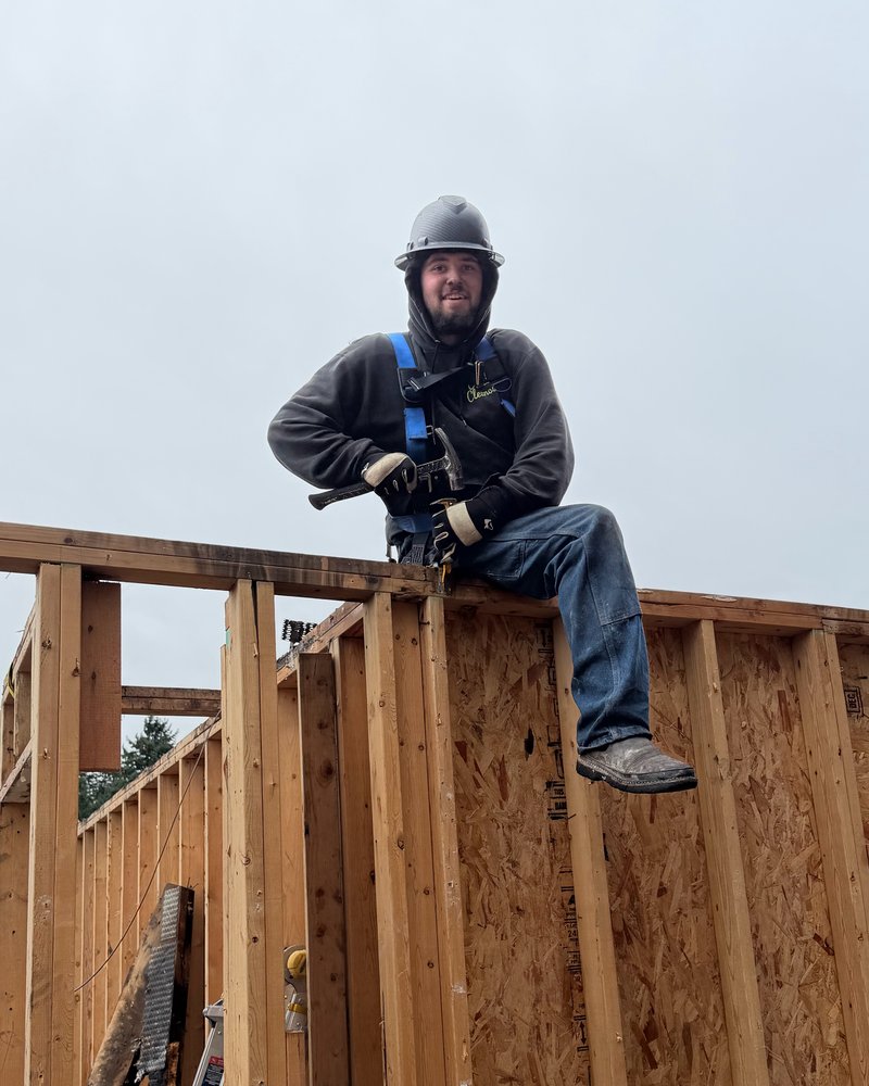 Jeffrey, Classic Cleanouts demolition team lead, in a hard hat and safety harness on top of a framed wall